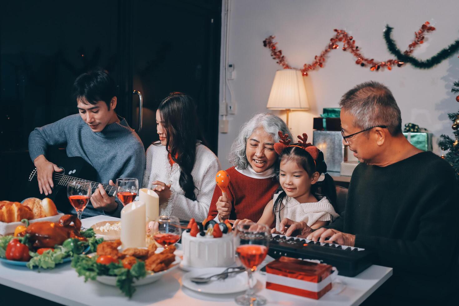 Multi-Generation Family Celebrate Christmas At Home Wearing Santa Hats And Antlers Opening Presents photo