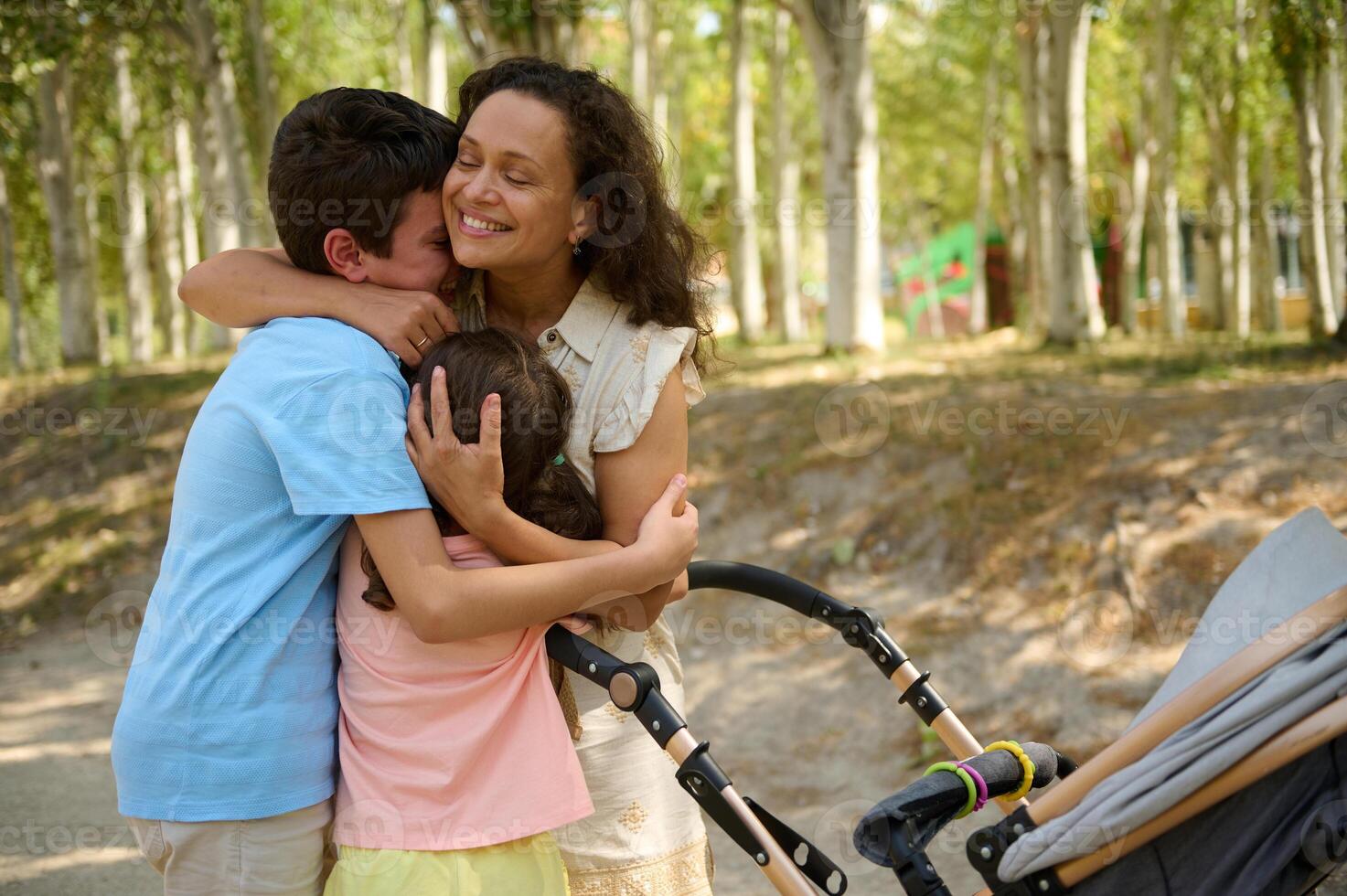 Mother embraces children while enjoying a stroll in the park photo
