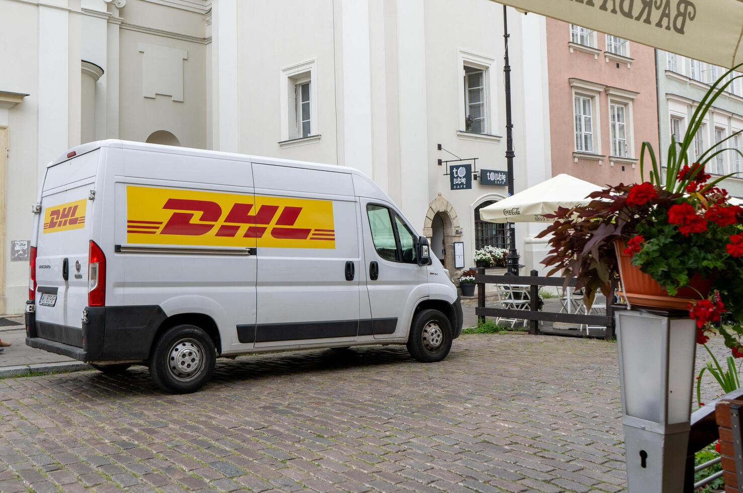 Delivery by DHL. White minibus on the street, delivery of settlements and documents. Poland, Warsaw - July 26, 2023 photo