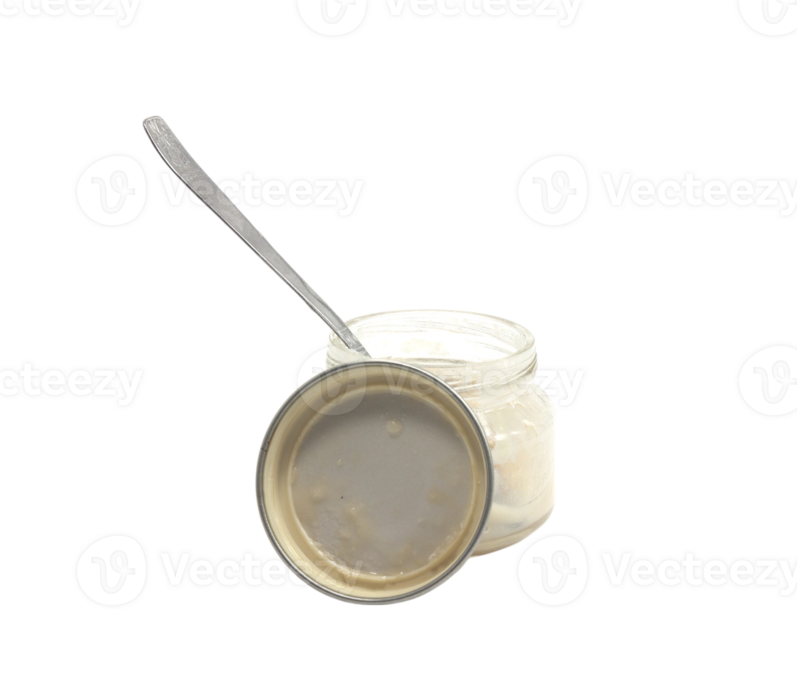 A jar of cream with a spoon on top png