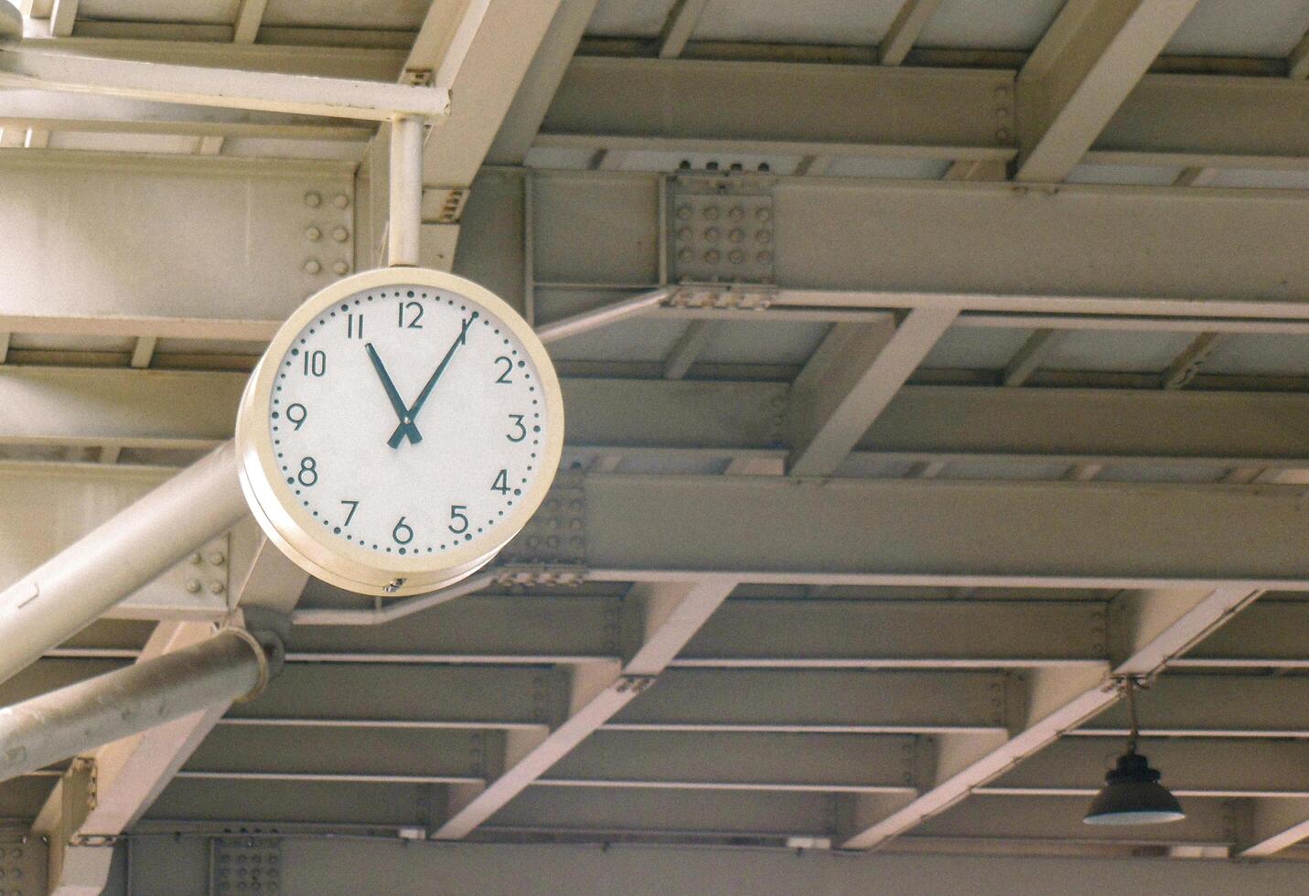 A clock hanging from the ceiling of a train station photo