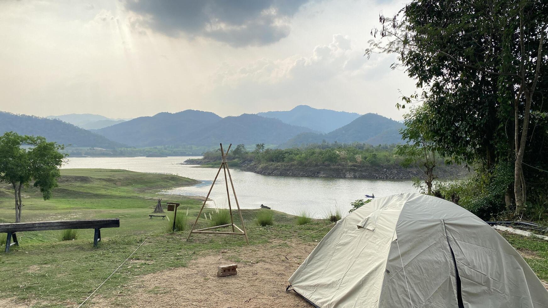 A tent is set up on the grass near a river photo