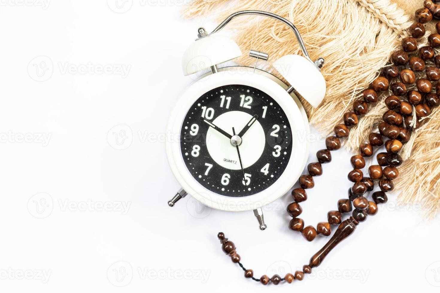 Time to break the fast, alarm clock and prayer beads on a white background. photo