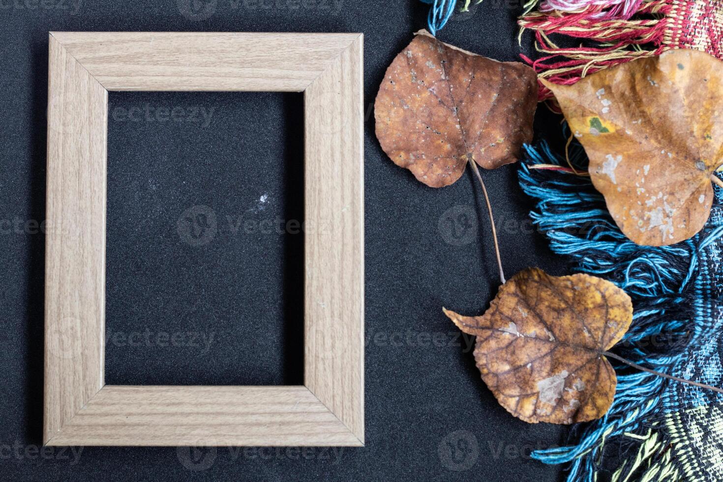 Autumn concept. Top view photo of wooden photo frame of yellow maple leaves and plaid on isolated black background with empty space