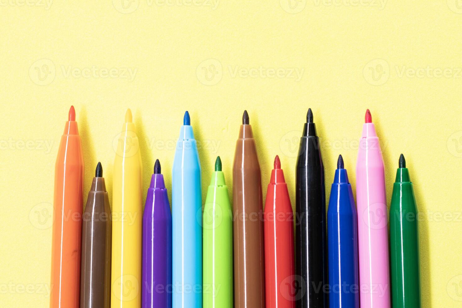 Colored markers isolated on yellow background photo