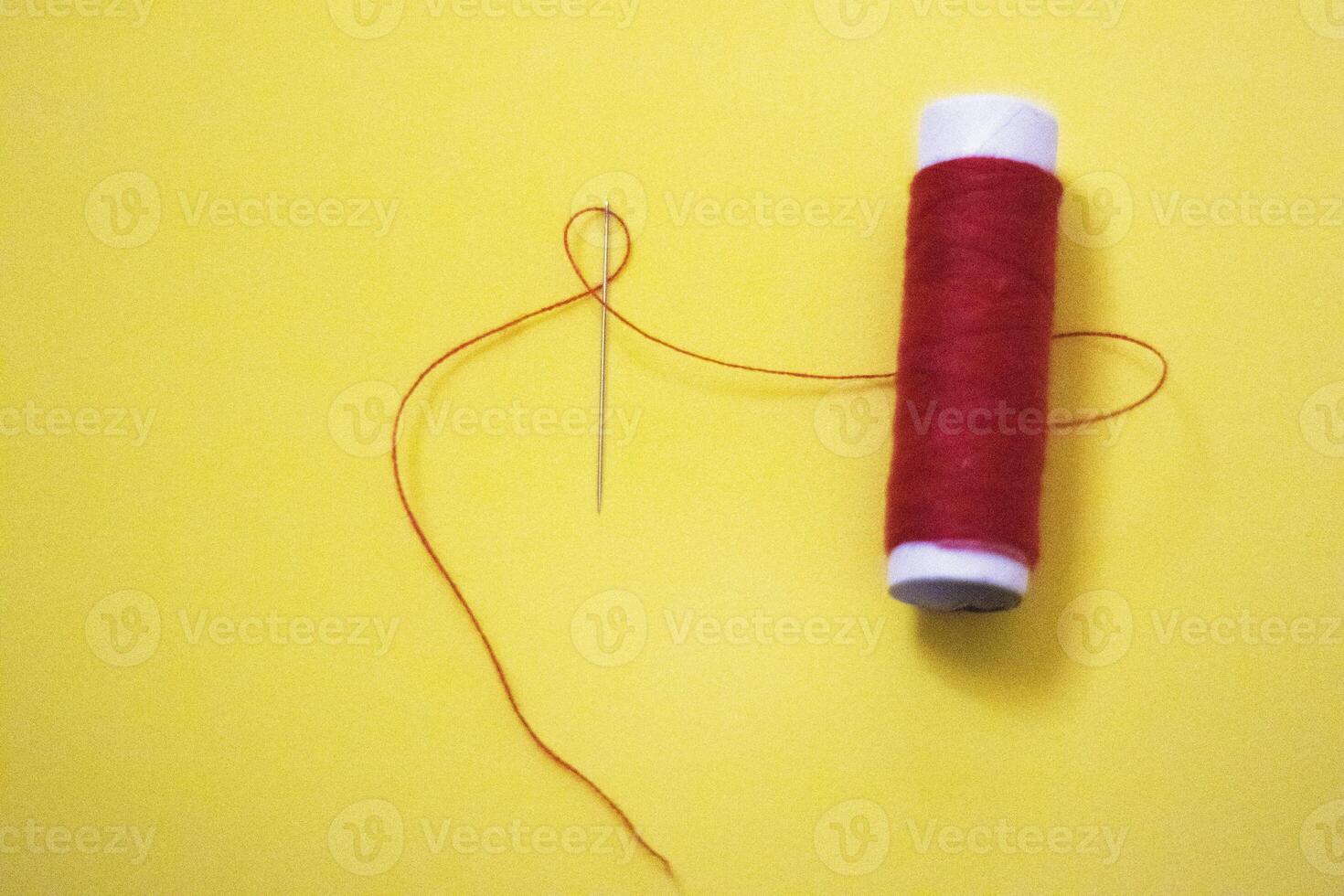 spool of thread with a needle on yelow isolated background photo
