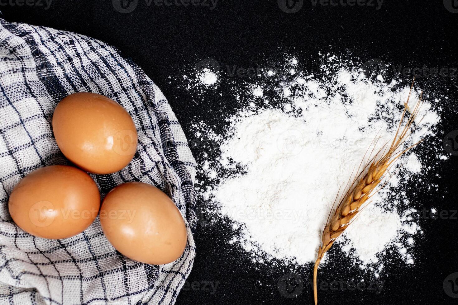 Flour and eggs on black table. Cooking process photo