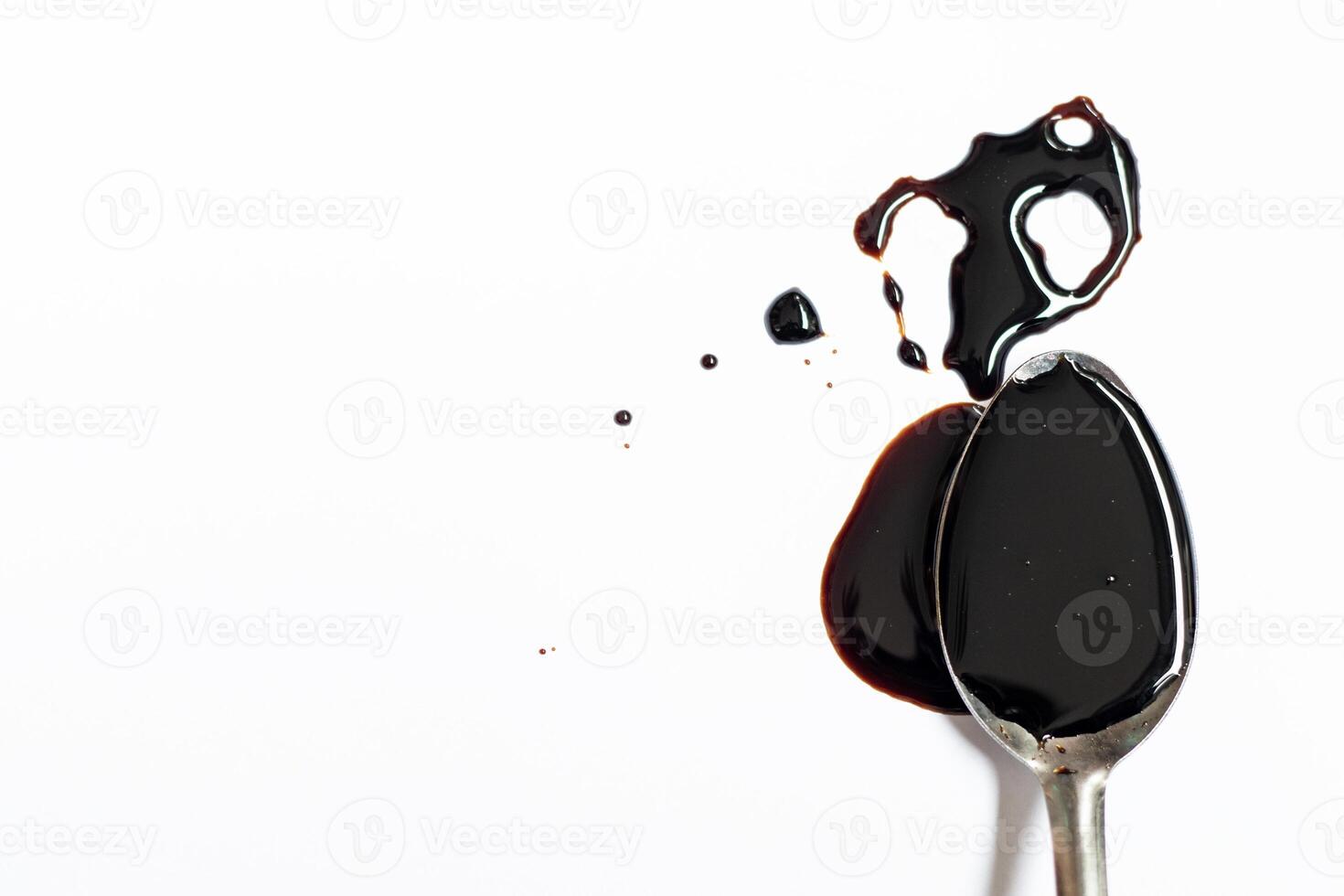 Soy sauce flowing over a spoon isolated on white background photo