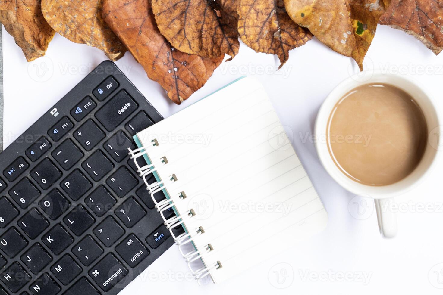 White autumn empty copy space with laptop, coffee, notebook and yellow leaves. Top view. Concept table photo