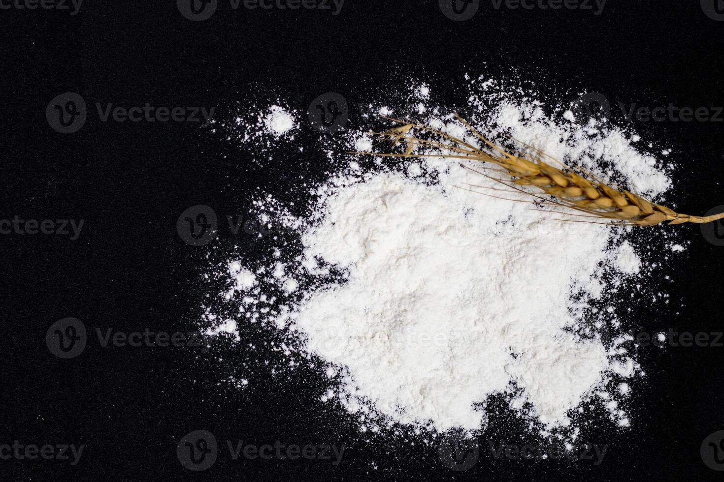 Wheat ears and flour on black background photo