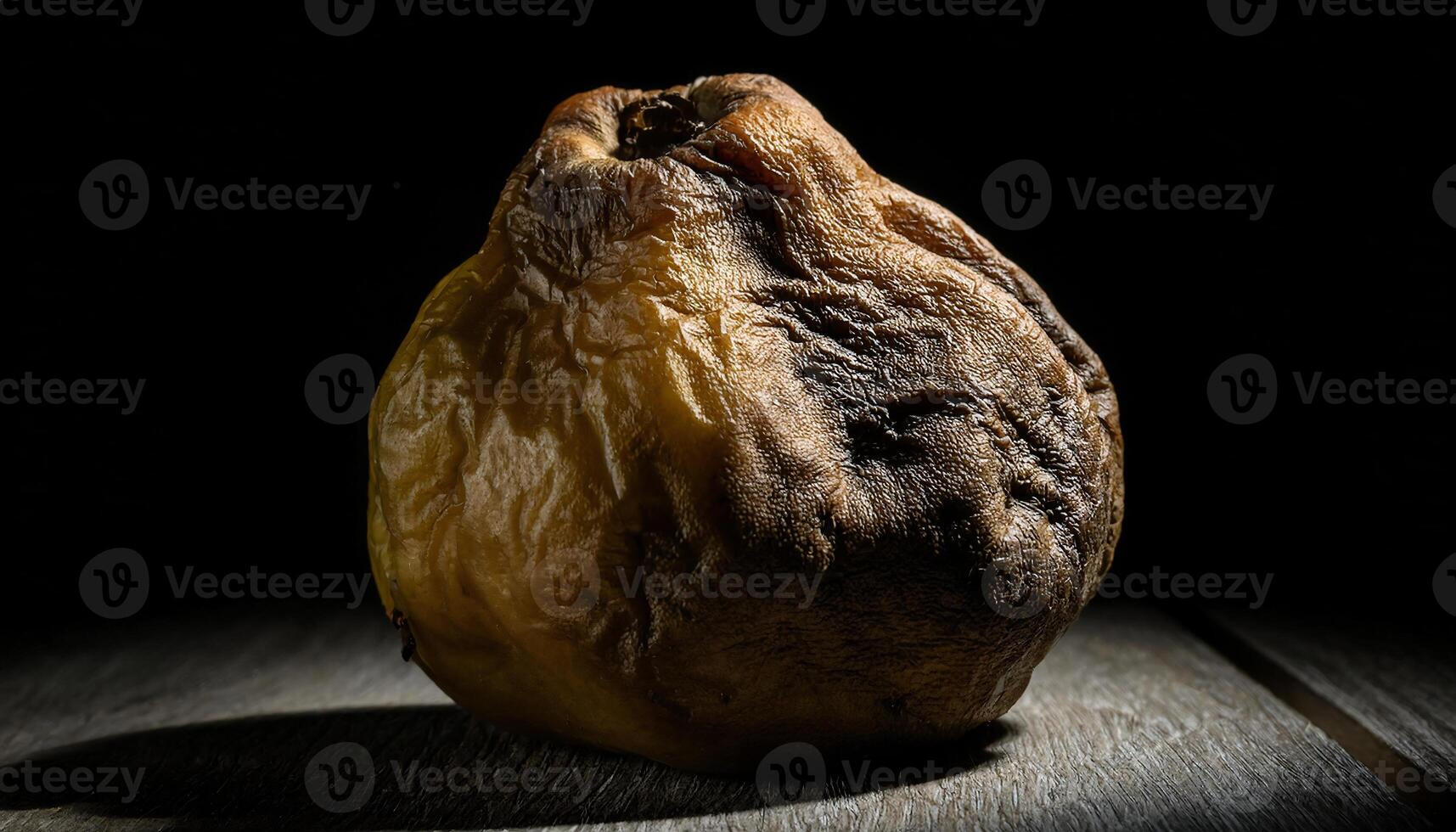 close-up of a wrinkled and discolored spoiled quince under dramatic lighting highlighting its natural decay photo