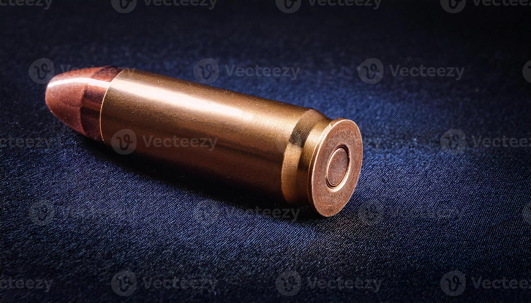 close-up of a single bullet with polished brass casing and detailed base engraving on a dark velvet surface under studio lighting photo