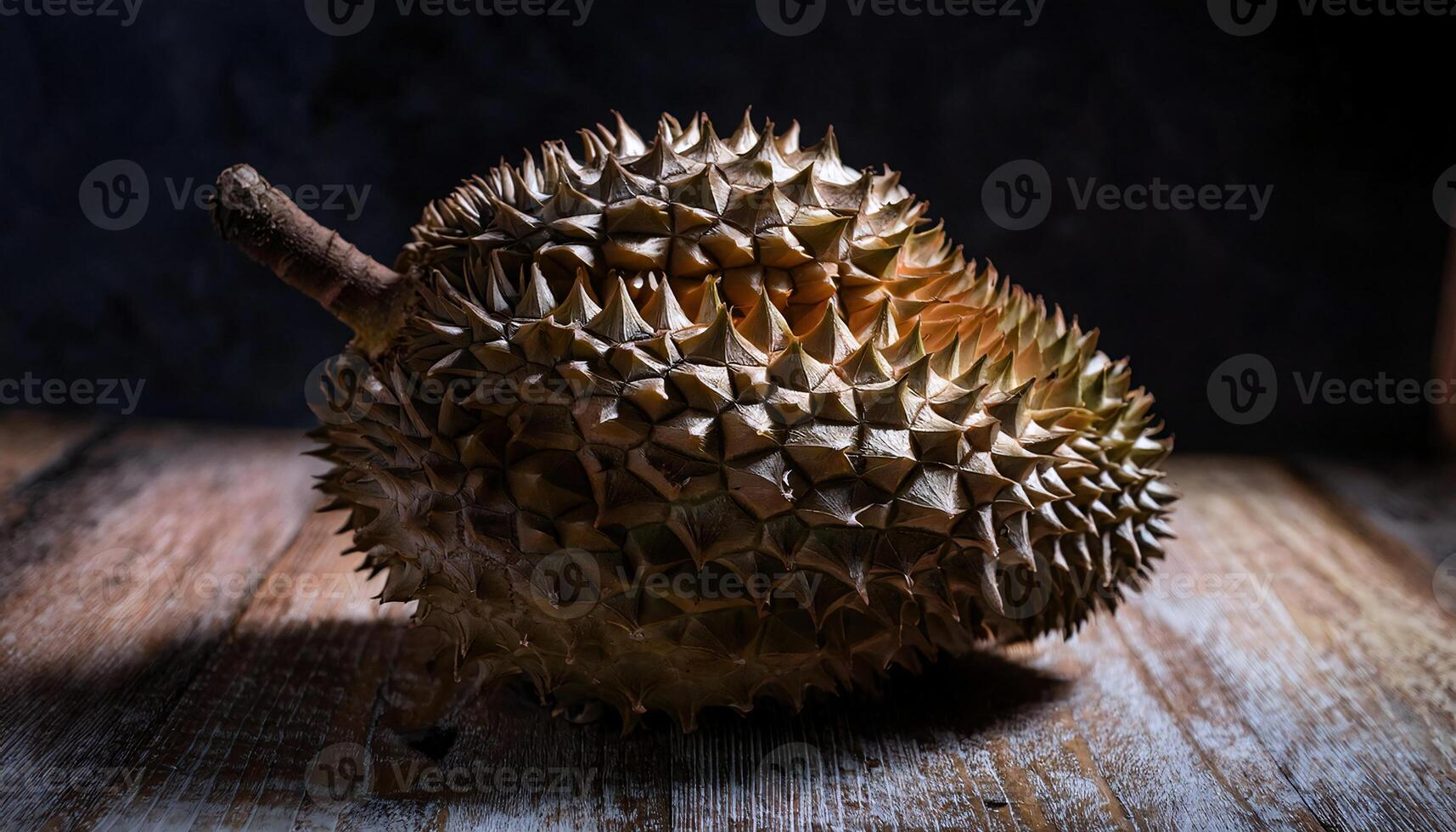 close-up of a rotting durian with browning spikes and soft mushy flesh under moody lighting on a wooden surface photo