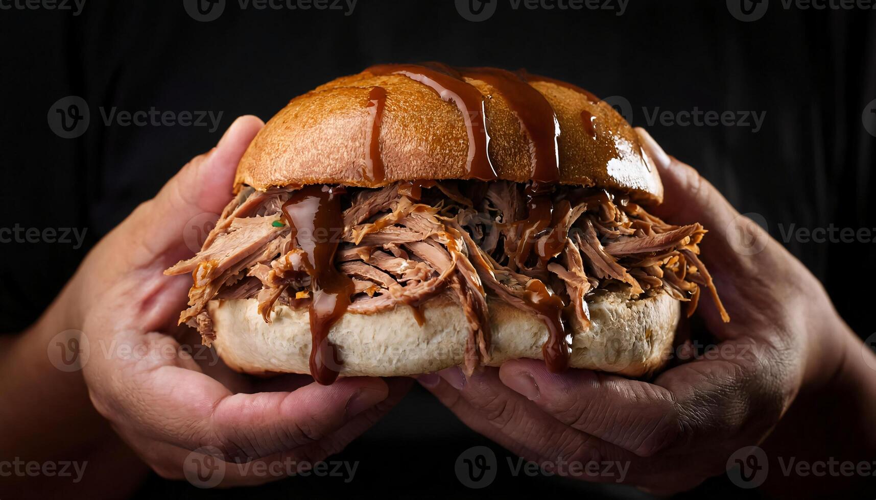 close-up of hands holding a pulled pork sandwich with barbecue sauce dripping down the sides against a dark background photo