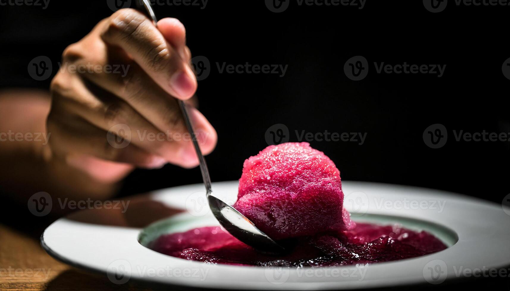 close-up of a chef shaping a perfect quenelle of vibrant red sorbet with a spoon, highlighting precision and dessert presentation in fine dining photo