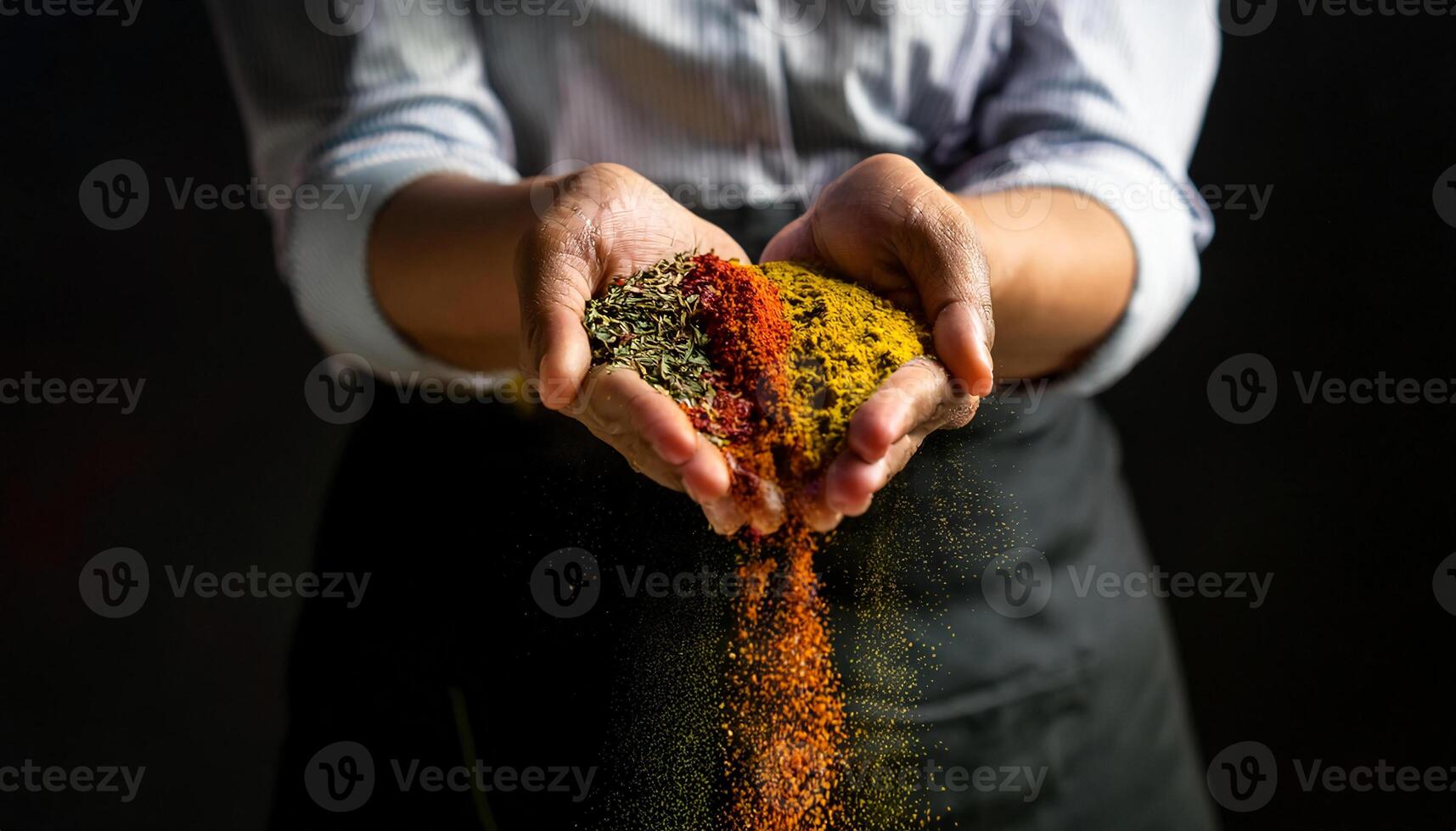 close-up of a chef holding a handful of colorful spices with vibrant grains of seasoning spilling through their fingers against a dark background photo