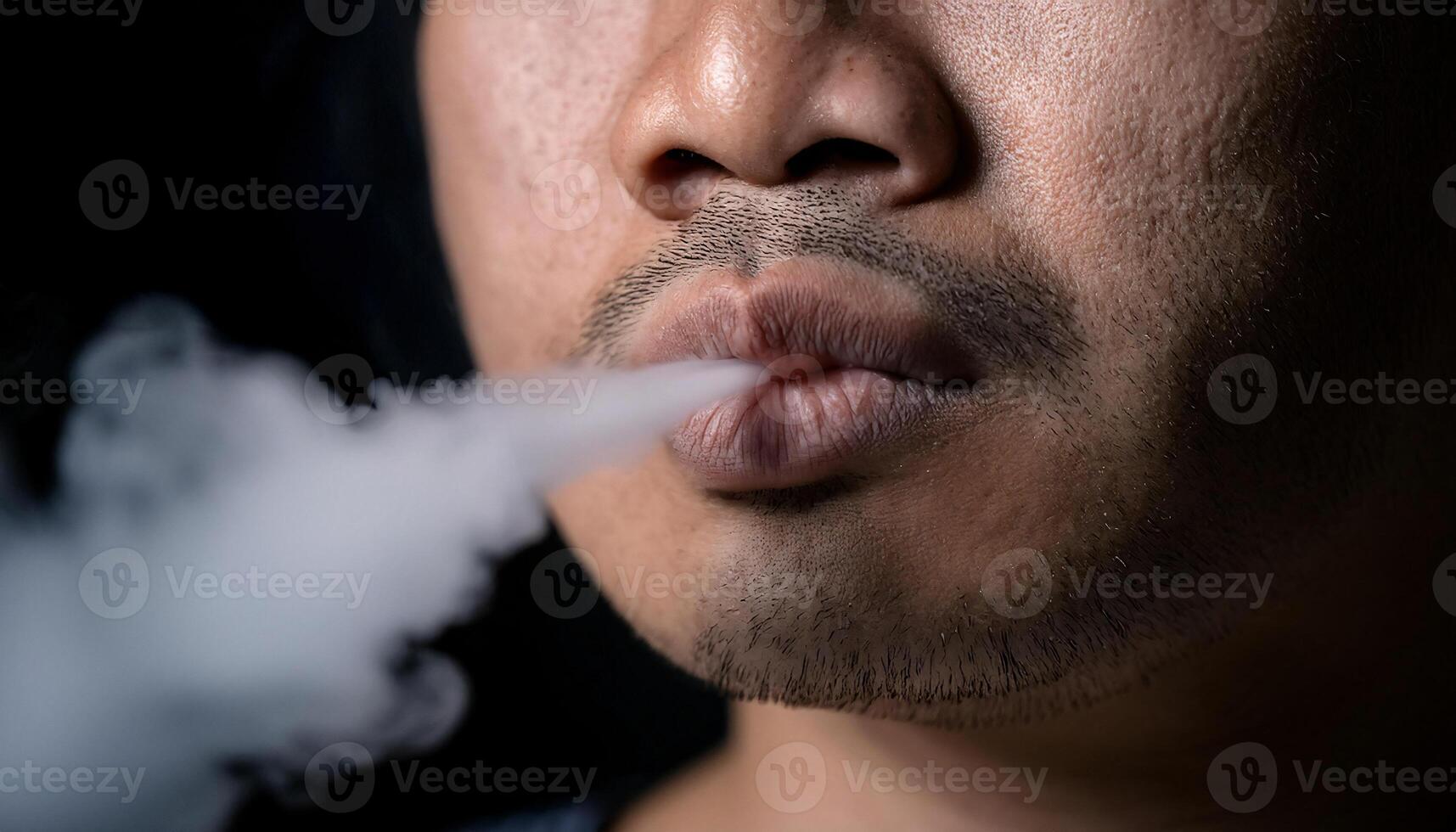 close-up of lips exhaling thick cigarette smoke in dark moody lighting with soft vapor trail photo