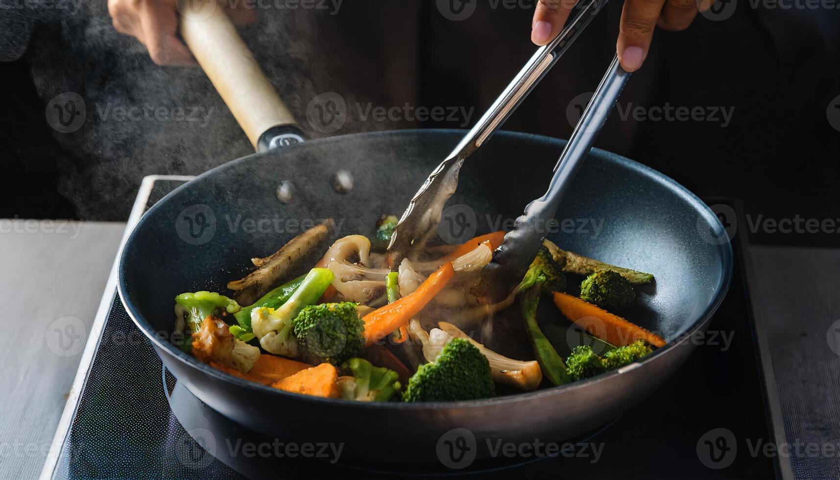 hands turning vibrant vegetables roasting in a steaming pan with tongs over high heat photo