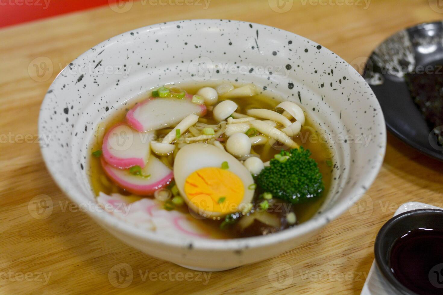 Japanese food concept. Shoyu Ramen with mushroom, pink and white fishballs, boiled egg, and green broccoli in a bowl. photo