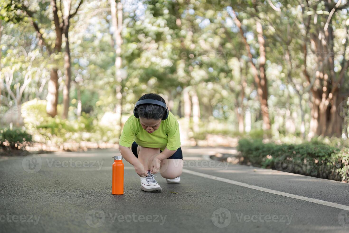Woman Jogging in a Lush Garden Setting with Headphones and Water Bottle, Embracing Fitness and Nature in a Serene Outdoor Environment photo