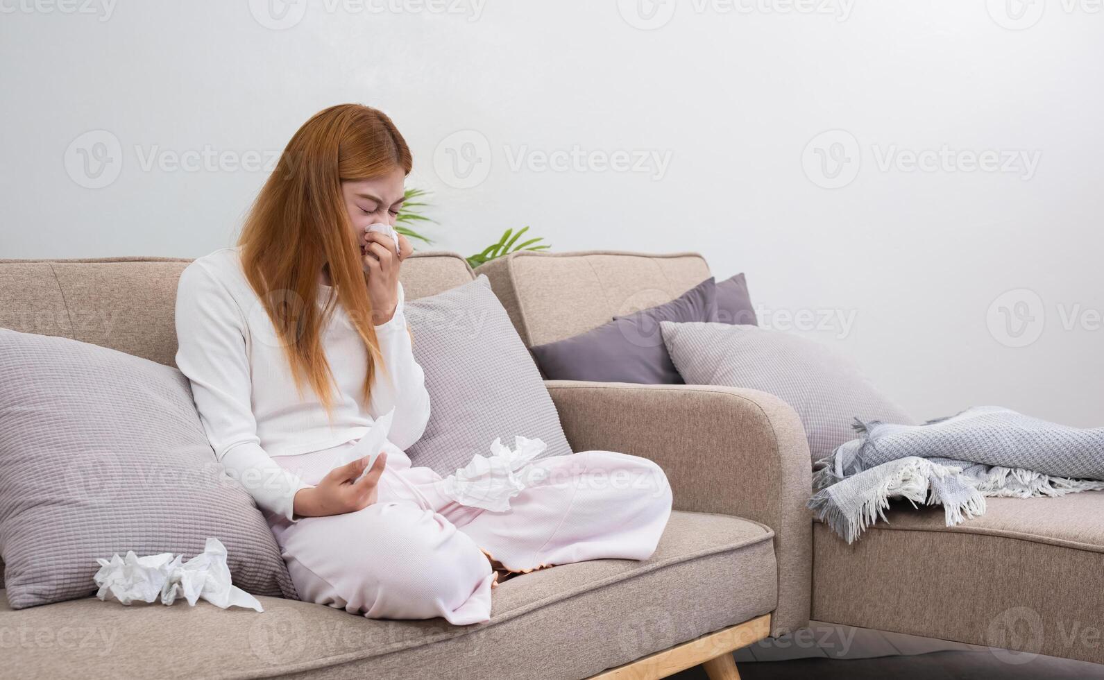 Young Asian woman with cold and allergies feels sick and sneezes on a day of resting at home. photo