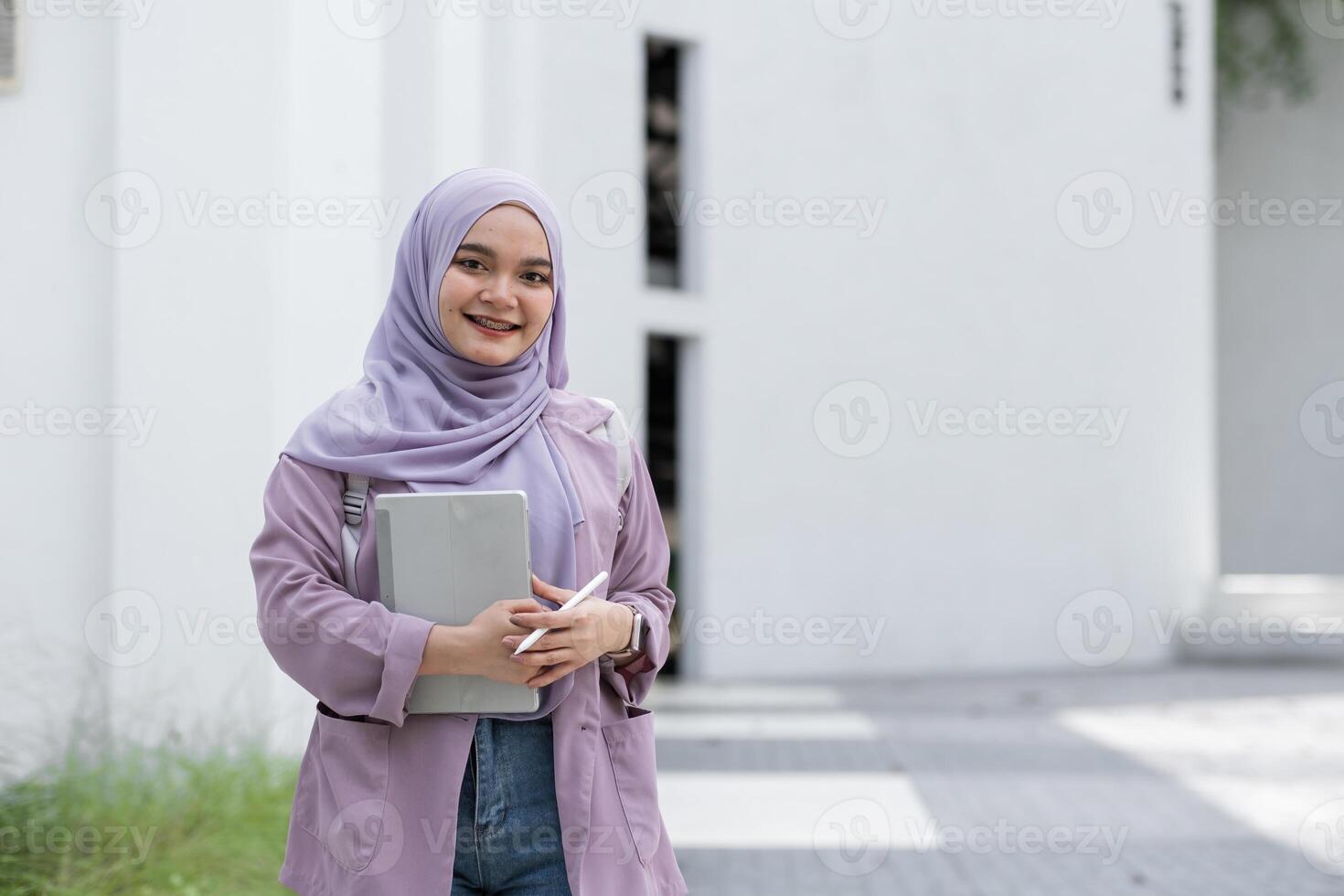 Confident Muslim Girl Student in Hijab Holding Books and Smiling Outdoors, Embracing Education and Modernity in a Bright Urban Setting photo