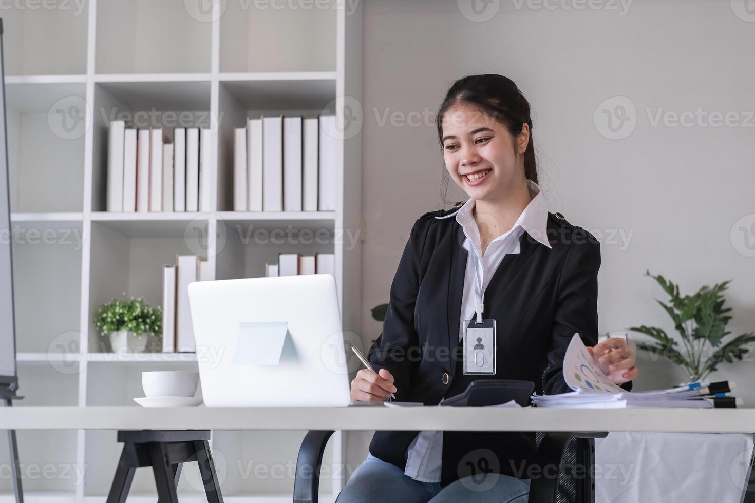 Accountant sitting with financial documents, using laptop, calculating financial and tax figures for company on table in office photo