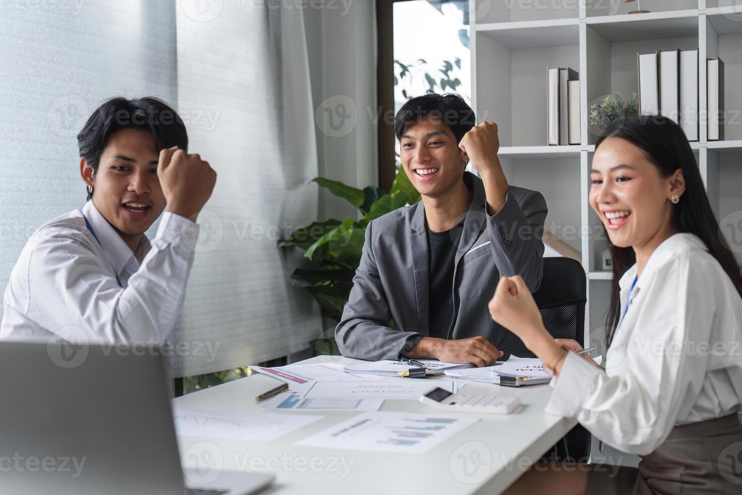 Happy Businessmen Celebrate Success Together in Modern Office Environment with Laptops and Documents photo