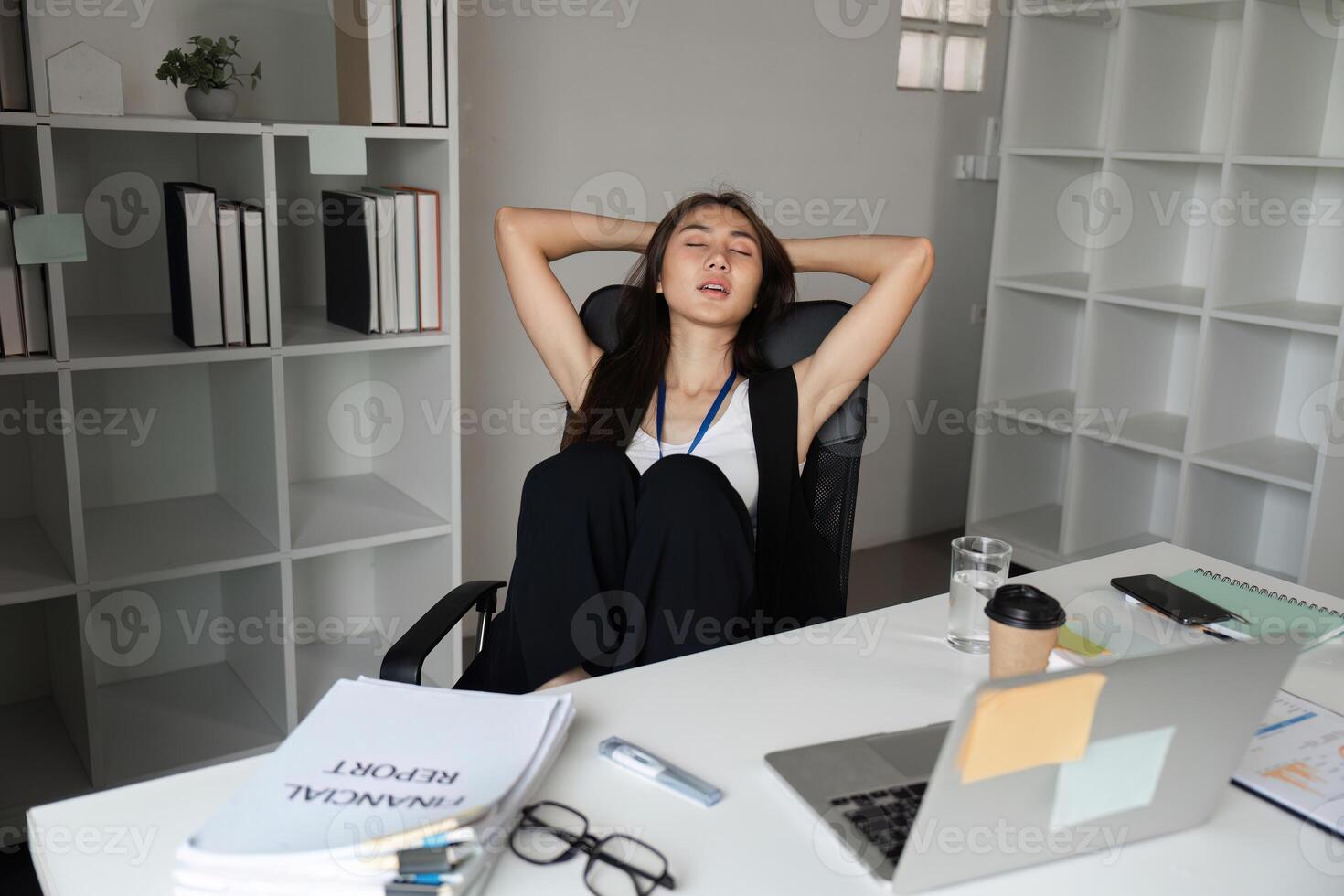 Exhausted Office Worker Taking a Break at Desk in Modern Workplace with Documents and Coffee photo