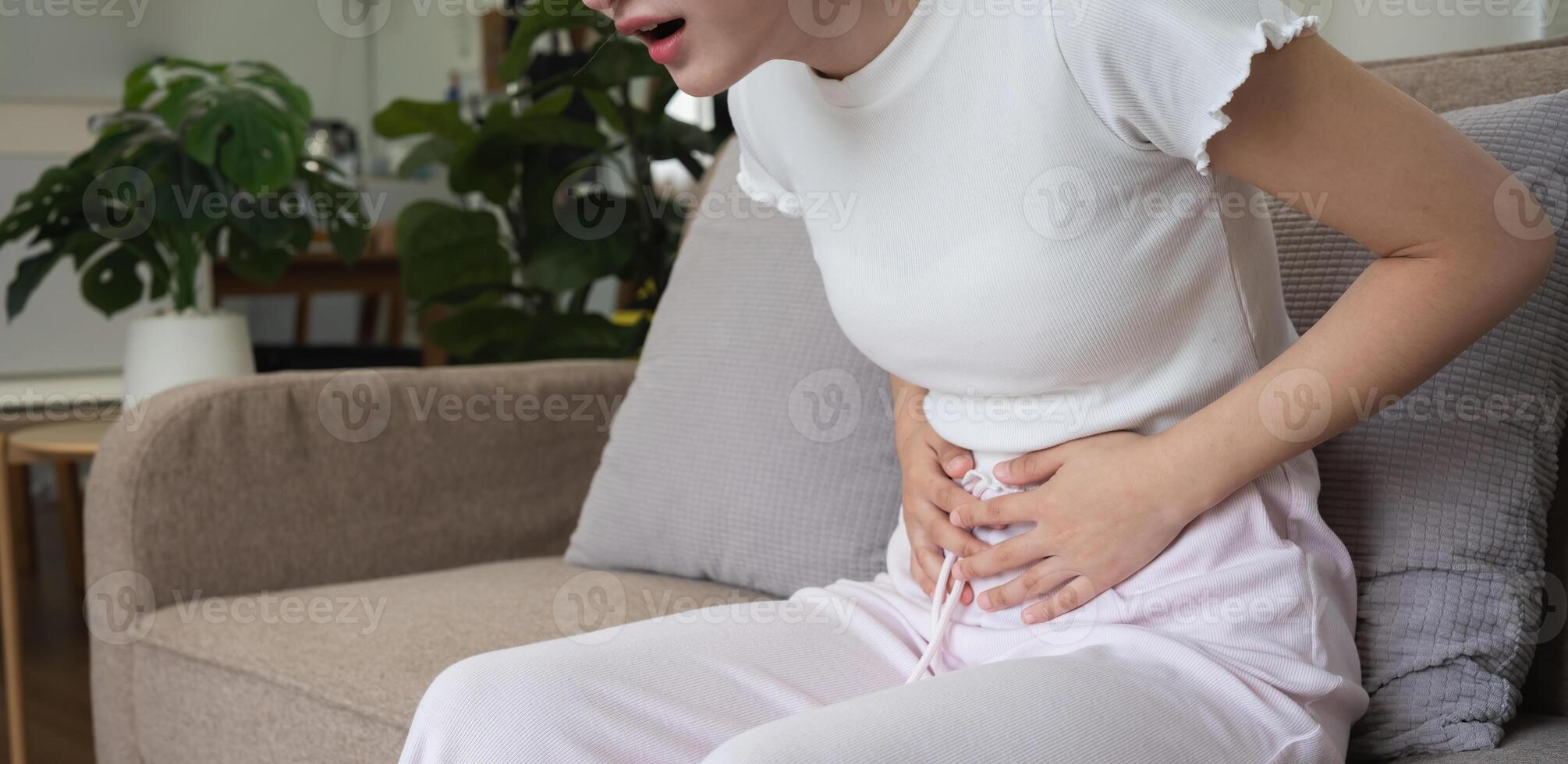 A young Asian woman with abdominal pain from diarrhea or menstrual cramps felt sick and touched her stomach with an unhappy expression. photo