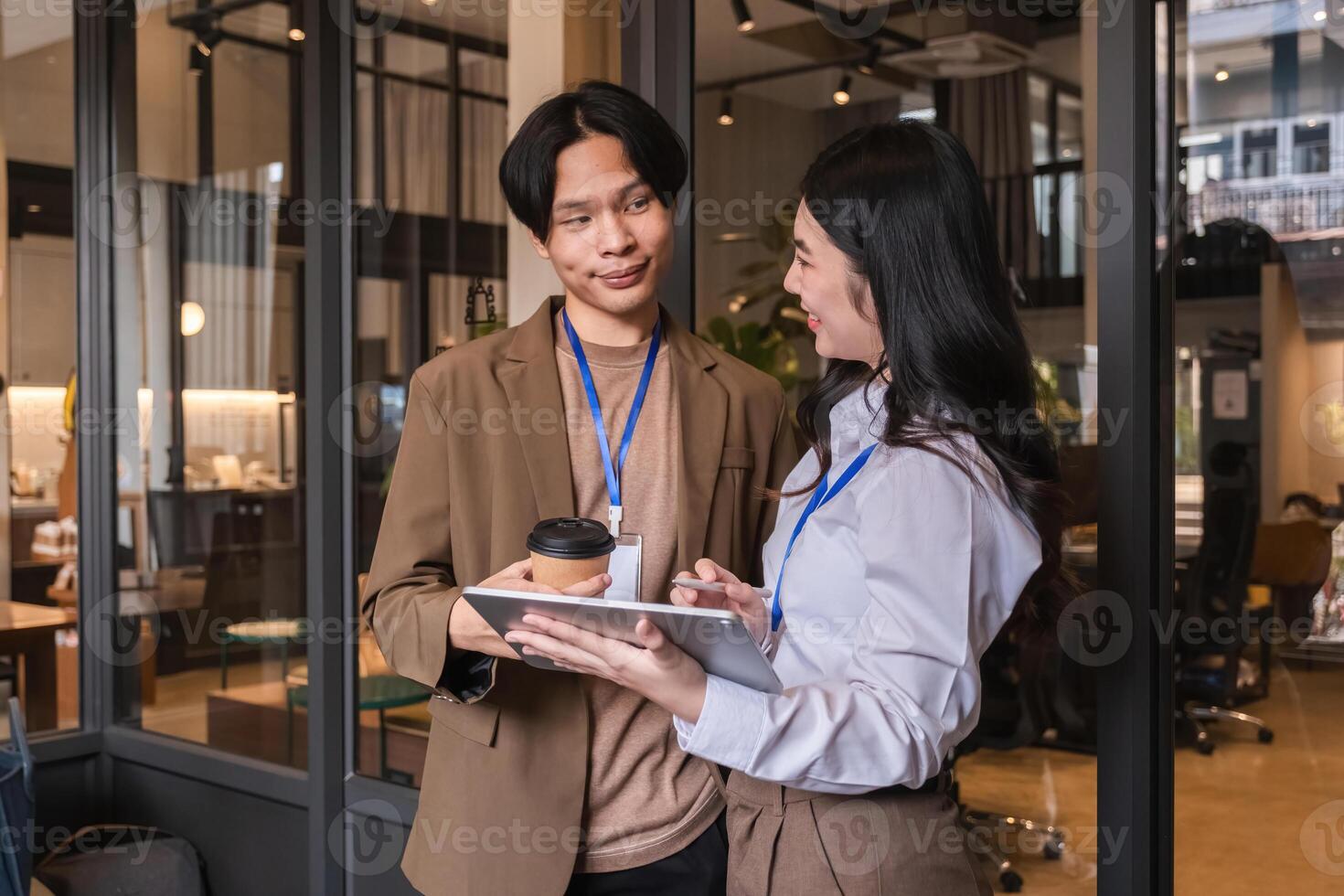 Young Asian business colleagues discussing project with tablet during break in modern office photo