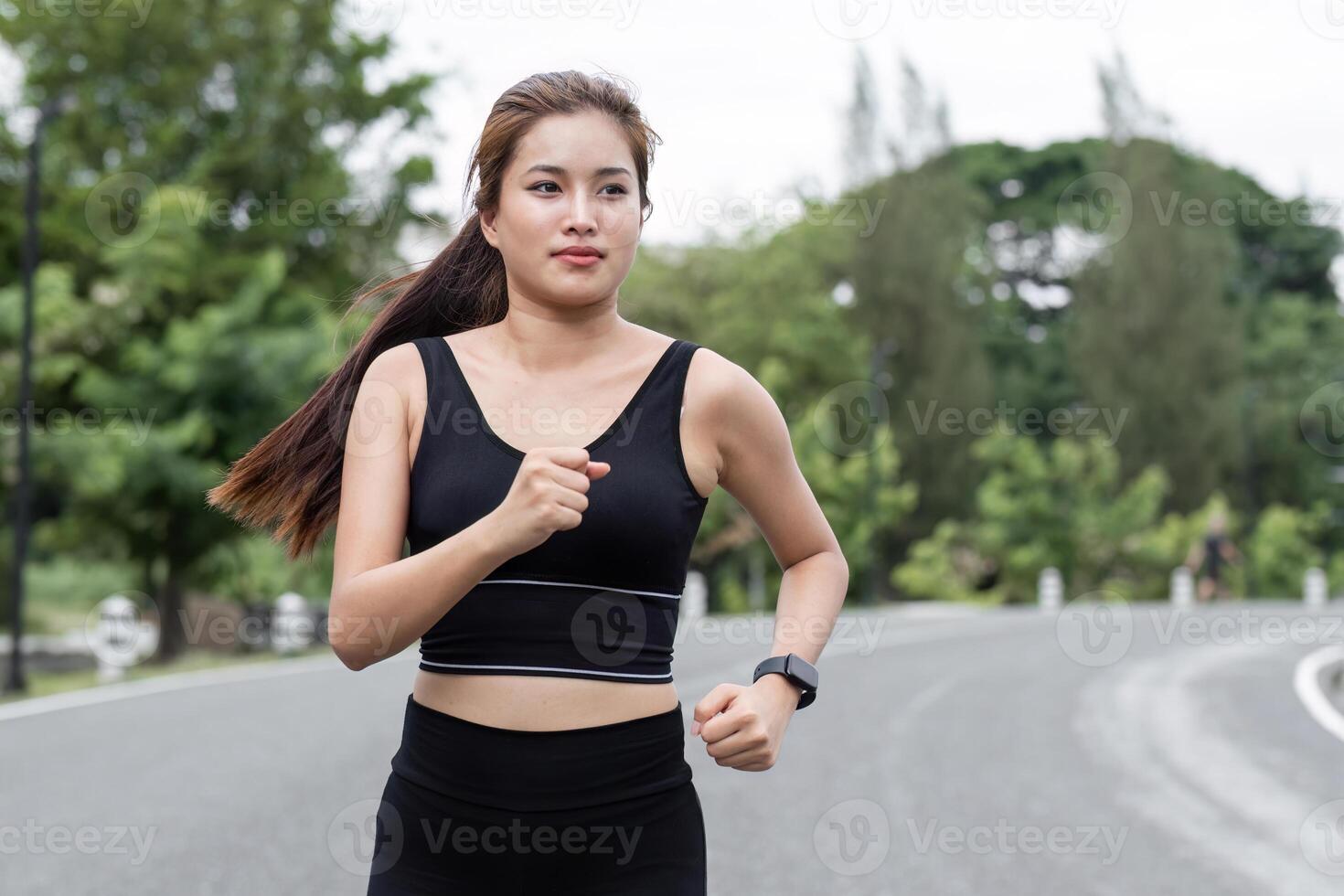 Woman Jogging in the Park on a Sunny Day, Embracing Fitness and Nature, Wearing Black Sportswear and Smartwatch photo