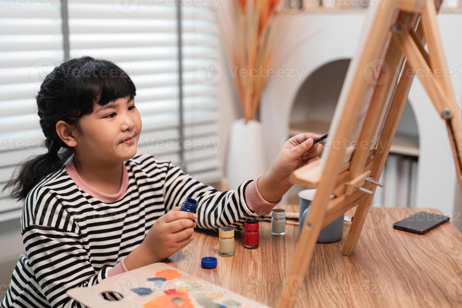 Cute Girl Painting with Acrylics on Canvas in a Cozy Home Studio Setting, Engaging in Creative Art Activity photo