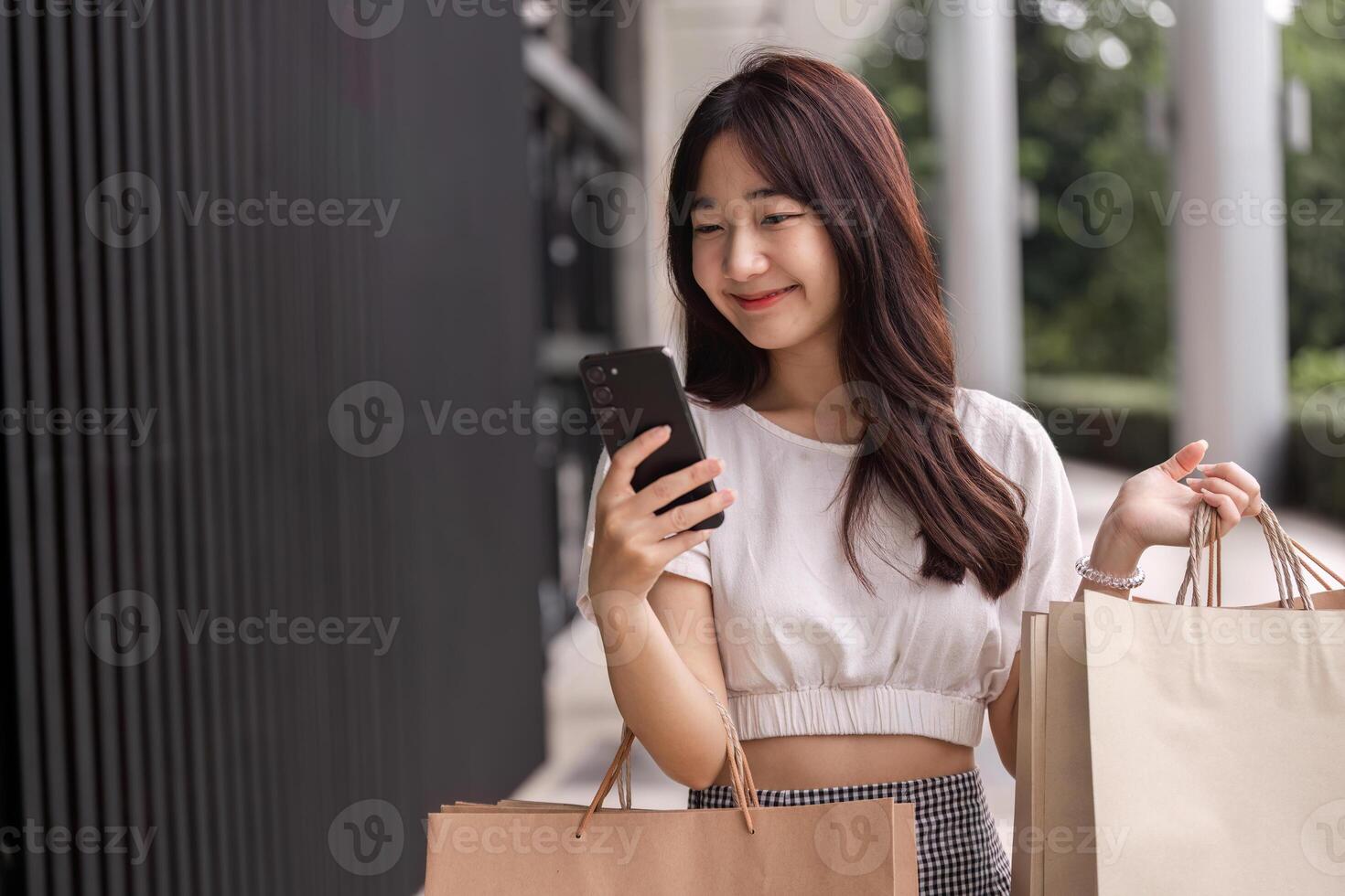 Young Woman Shopping with Paper Bag and Smartphone in Urban Setting, Smiling and Enjoying a Modern Retail Experience photo