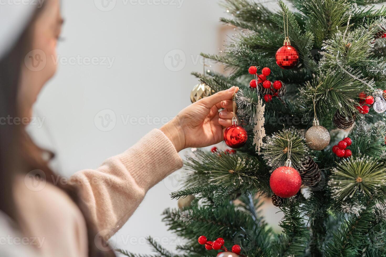 Young Woman Joyfully Decorating Her Room with Festive Christmas Ornaments and a Beautifully Lit Tree photo