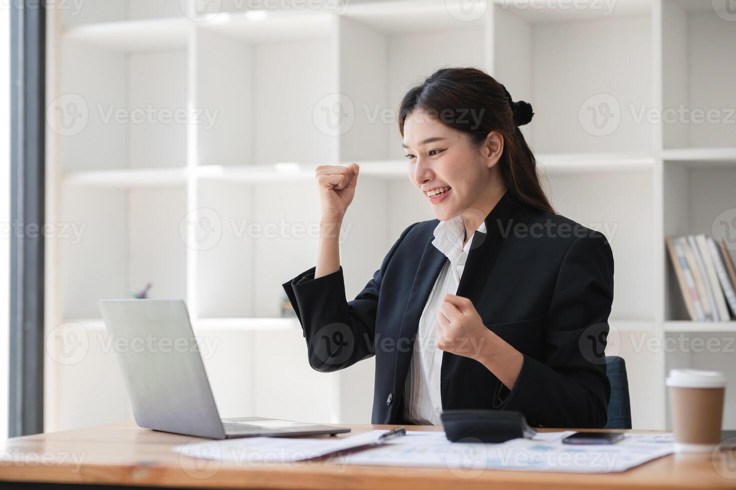 Confident Businesswoman Working on Laptop in Modern Office Celebrating Success, Professional Female Entrepreneur in Formal Attire, Corporate Environment, Productivity, and Achievement photo