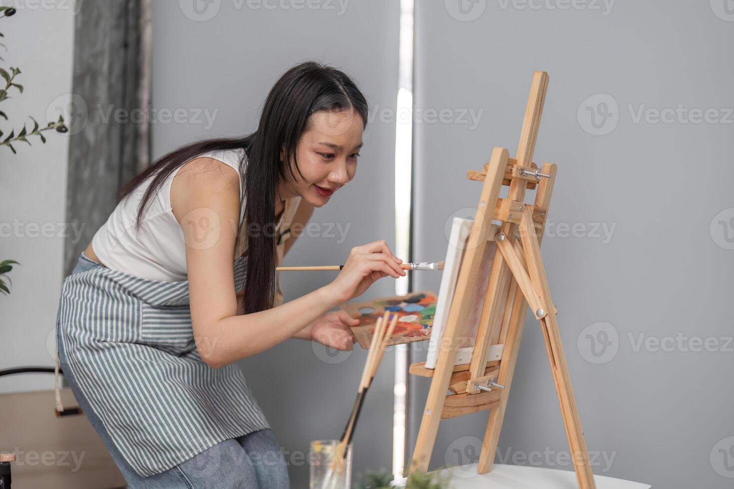Young Woman Drawing Picture on Easel Relaxing in Modern Room with Natural Light and Comfortable Atmosphere photo
