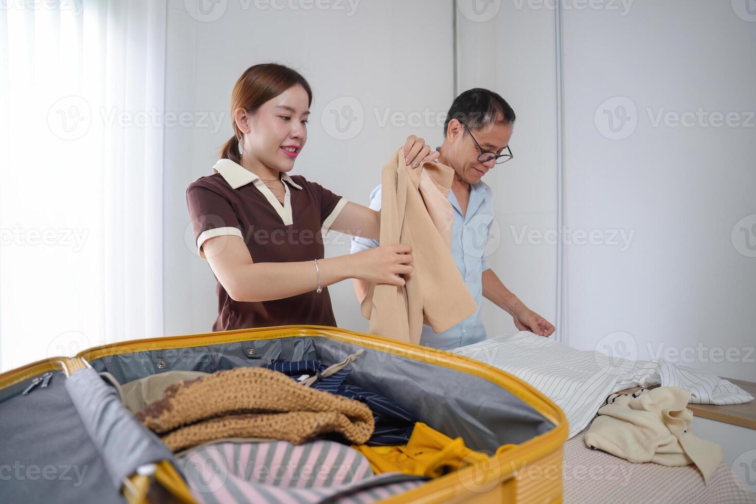 Father and Daughter Bonding While Folding Clothes and Packing a Suitcase for a Trip in a Modern Home photo