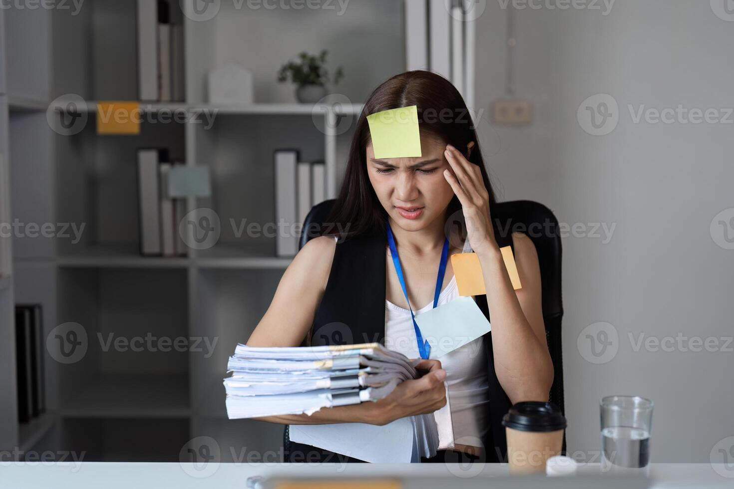 Focused Businesswoman Juggling Tasks in Modern Office Setting with Documents and Sticky Notes photo