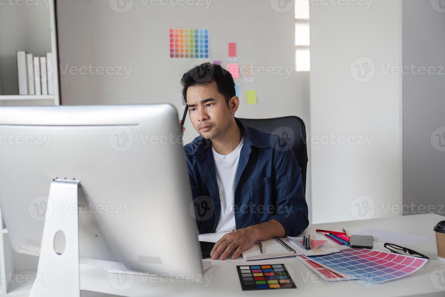 Graphic Designer Focused on Project Planning in Modern Office with Color Swatches and Computer photo