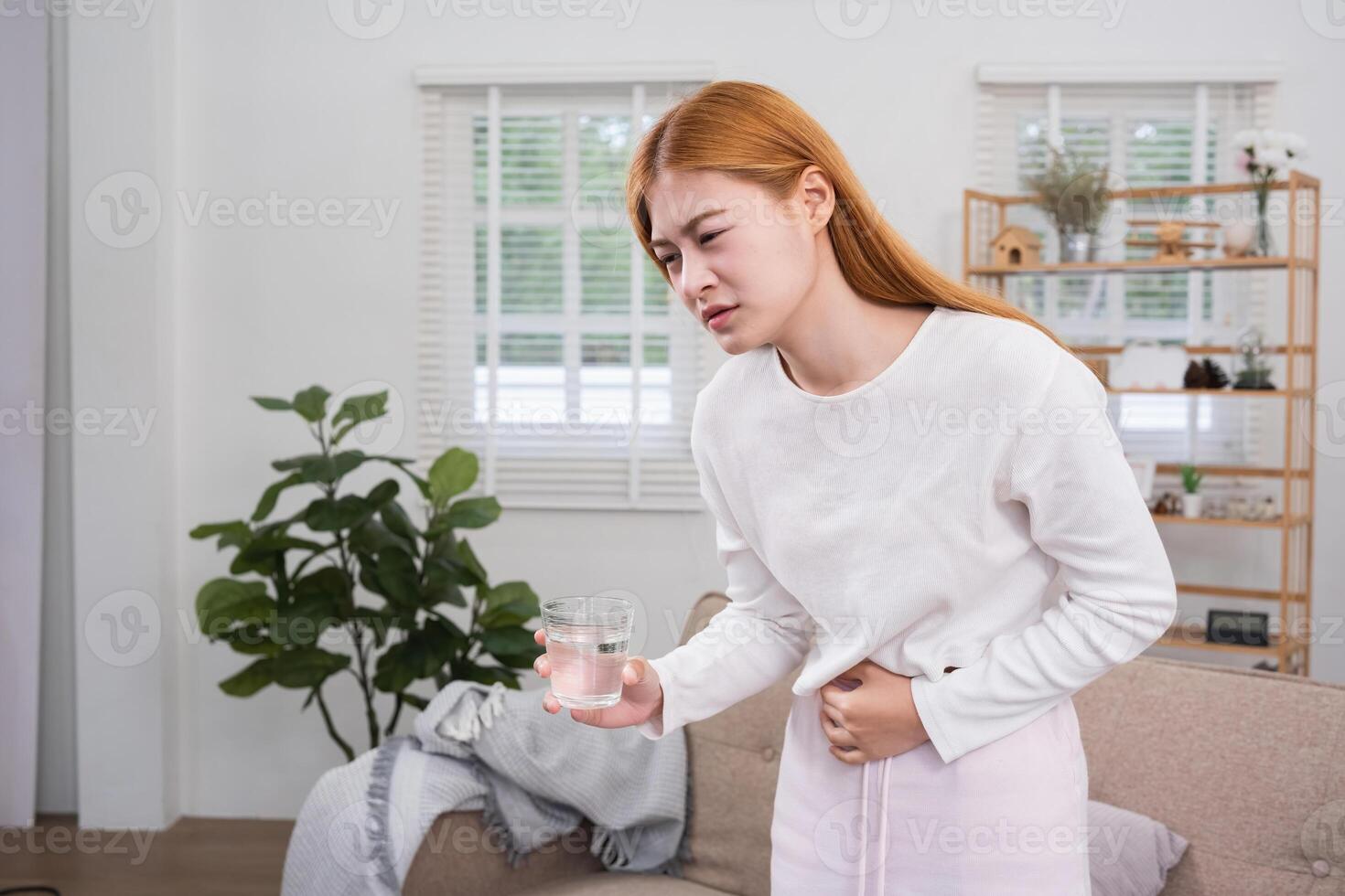 A young woman with stomach pain from diarrhea or menstrual cramps felt sick and touched her stomach with an unhappy expression. photo