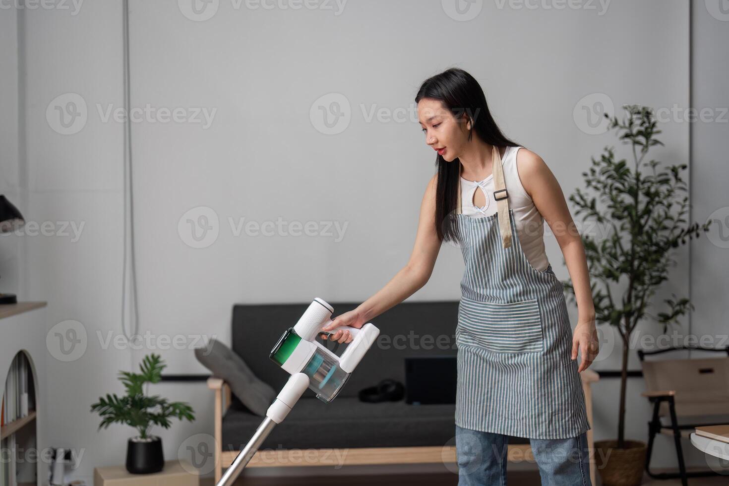 Young Woman Vacuuming and Cleaning Living Room in Modern Home with Minimalist Decor photo