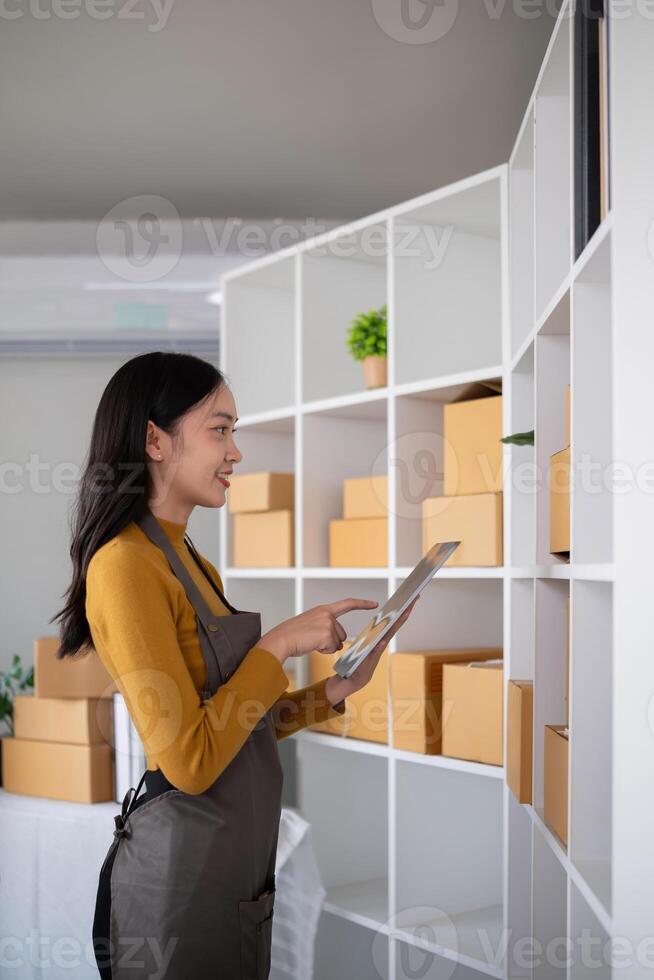 Young woman working in warehouse with packages using tablet for inventory management photo