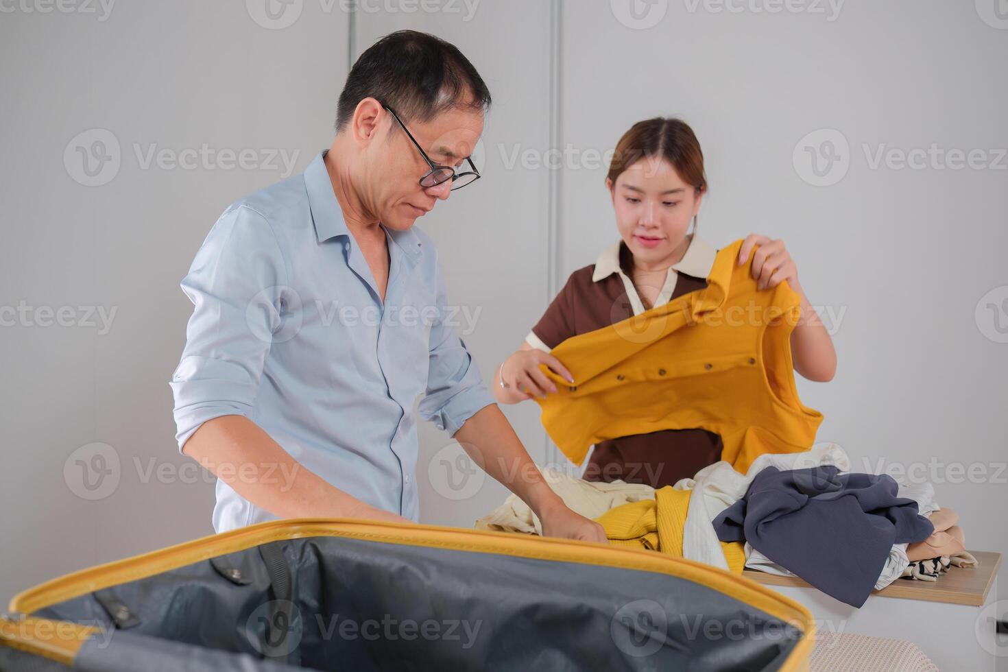 Father and Daughter Folding Clothes Together and Packing Them in a Suitcase for a Trip photo