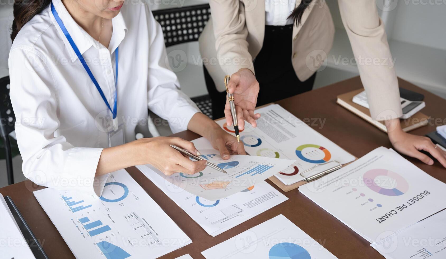 Businessman meeting marketing plan, using calculator to calculate numbers on stock market graph paper for analysis. Meeting to discuss company ideas photo