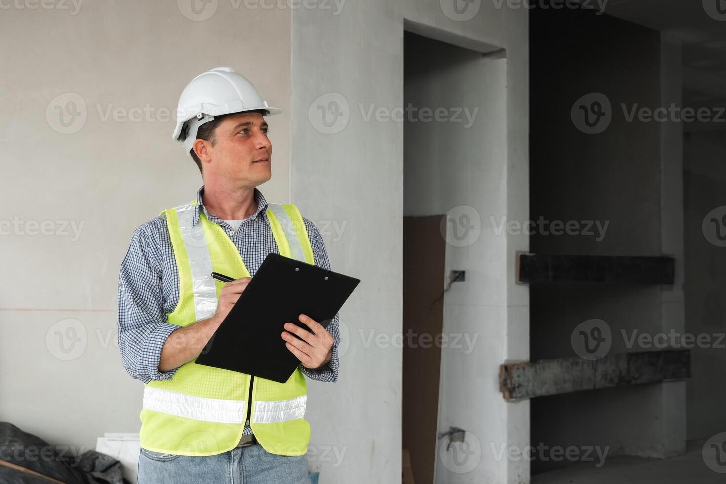 Young Engineer at Construction Site Wearing Safety Gear and Holding Clipboard, Inspecting Building Progress, Modern Architecture, Professional Worker, Construction Industry, Engineering Career photo
