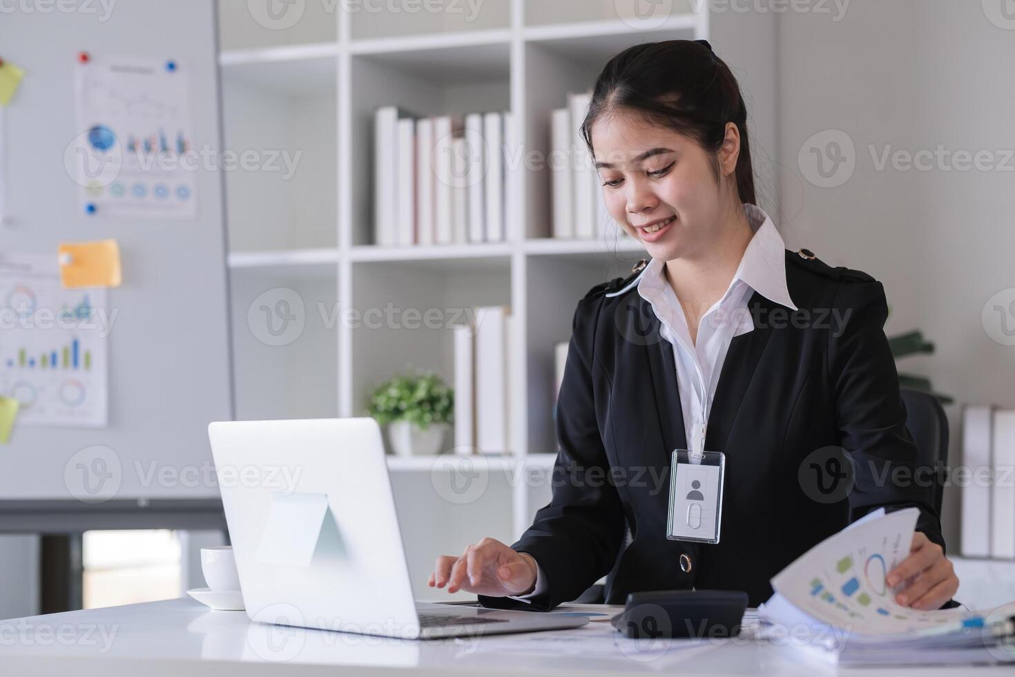 Accountant sitting with financial documents, using laptop, calculating financial and tax figures for company on table in office photo