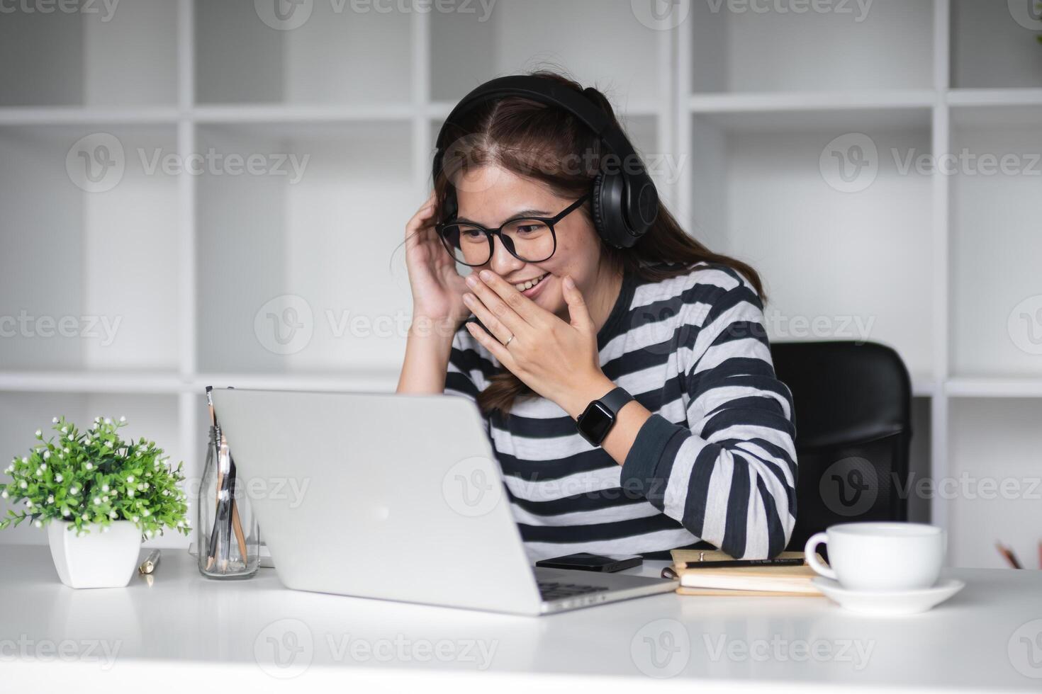 Beautiful accountant wears headphone to chat with coworkers via online call program on work from home day photo