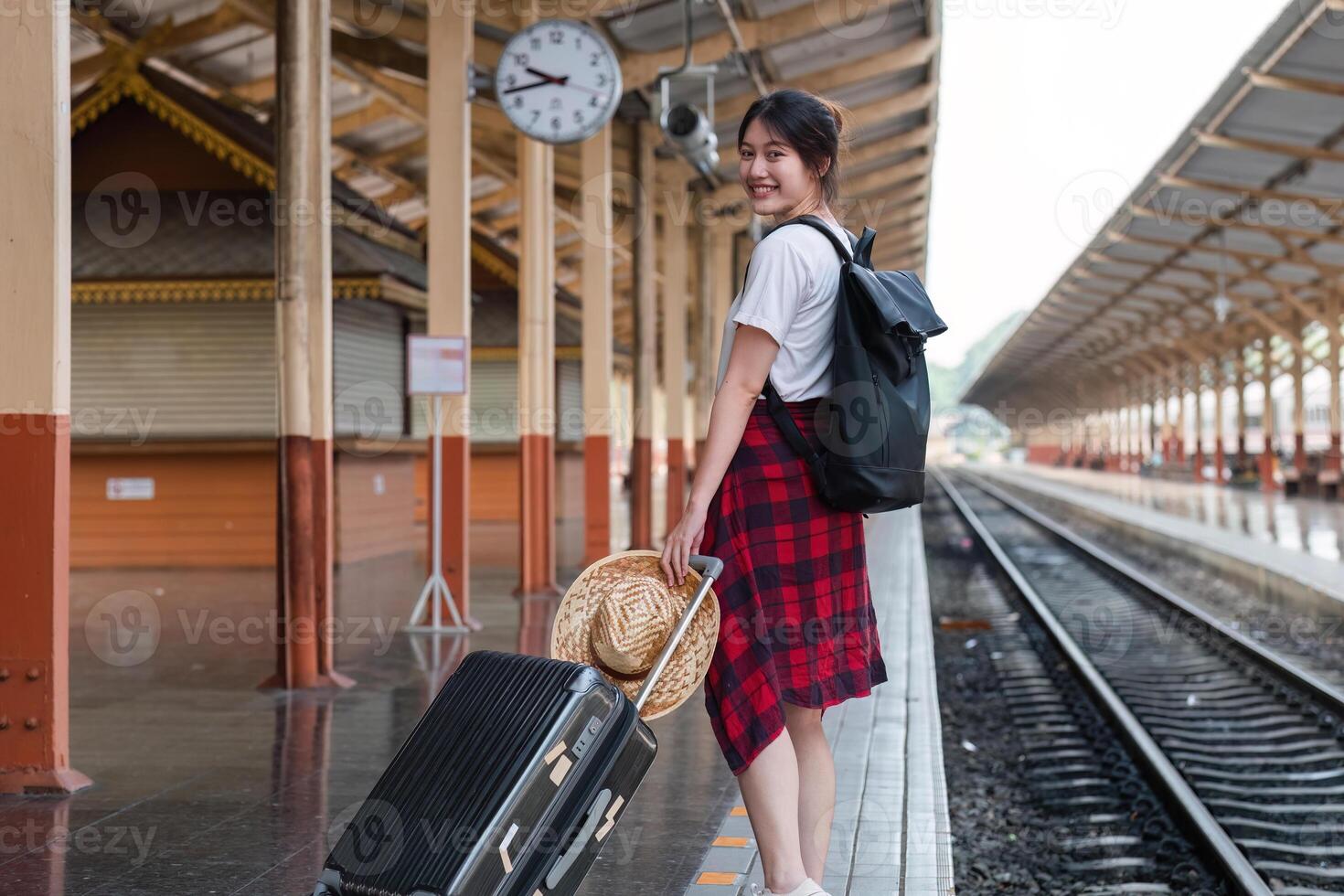 Cute Young Woman Standing at Train Station with Luggage, Ready for Travel Adventure, Smiling and Waiting for Train Arrival photo