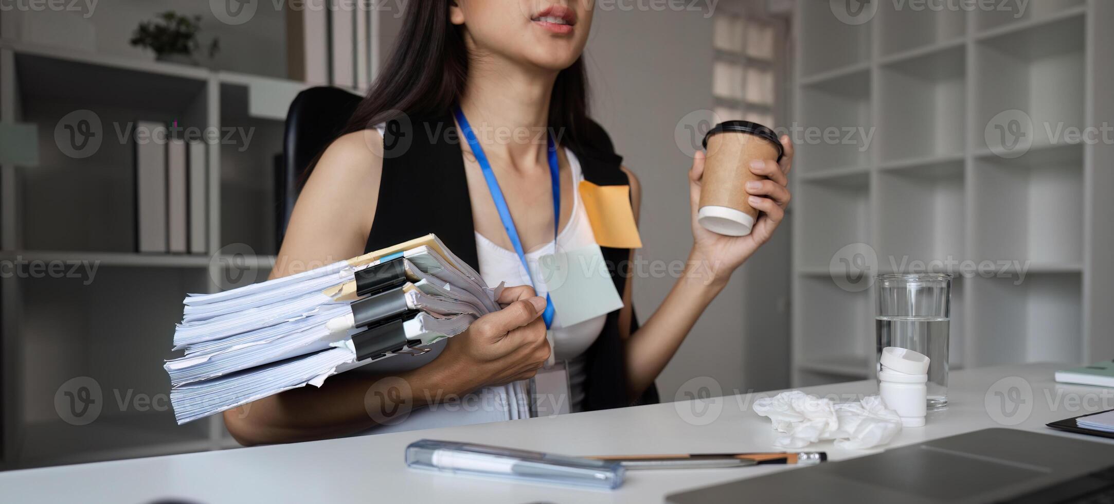 Focused Businesswoman Multitasking at Office Desk with Documents and Coffee in a Modern Workspace Environment photo